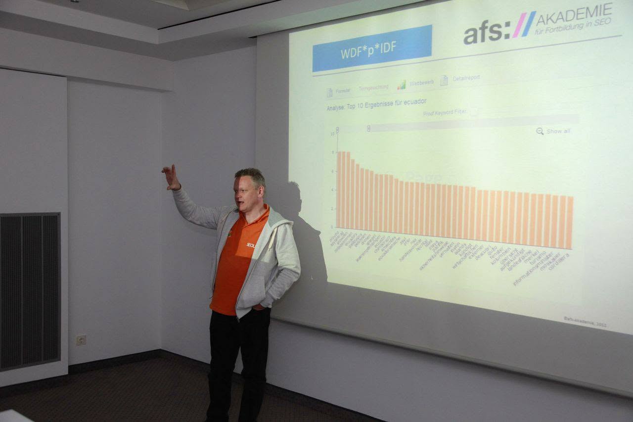 Leo Kobes zeigt vor einer Projektion auf eine Auswertung, im Bild das Logo der AFS Akademie