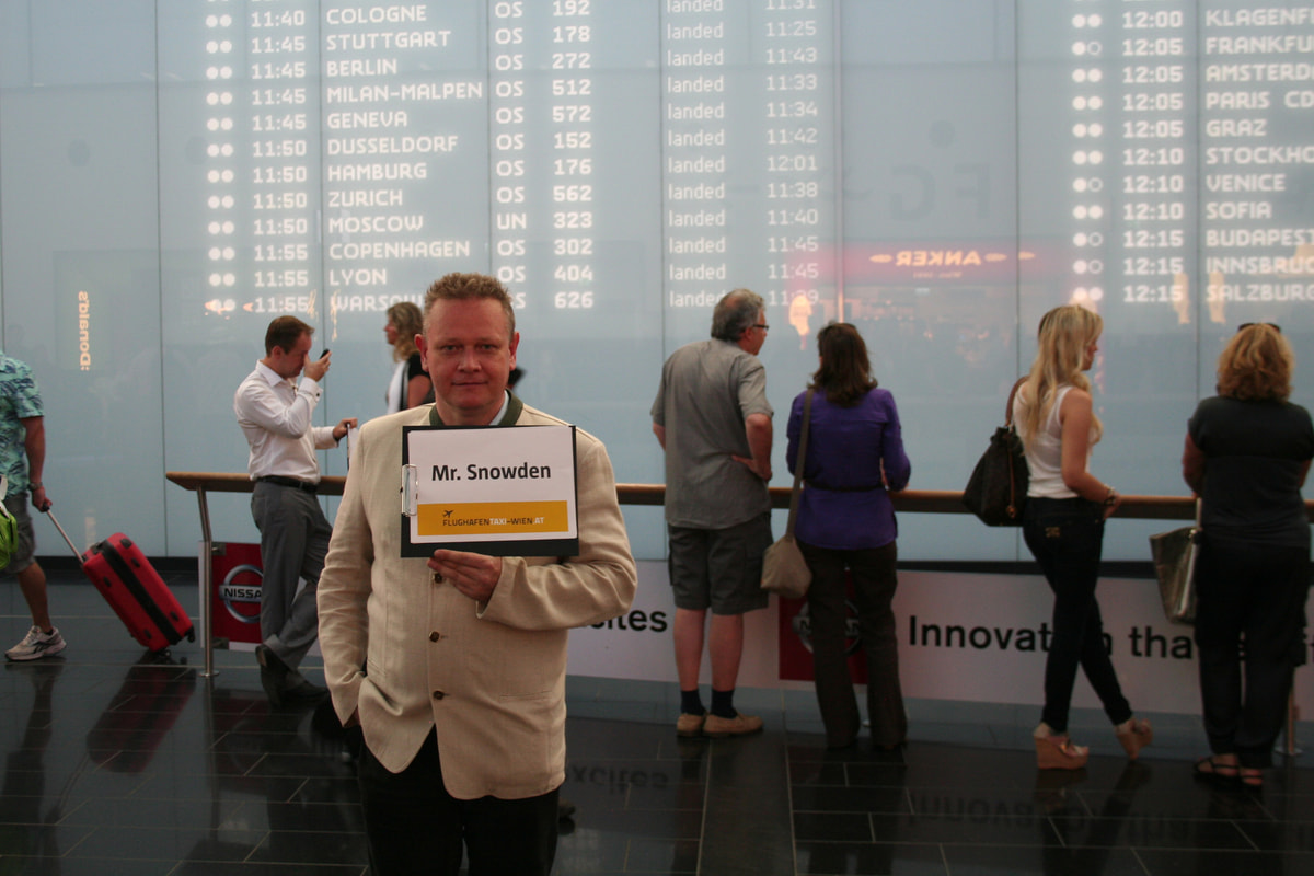 Leo Kobes als vermeintlicher Chauffeur mit einem Schild „Mr. Snowden“ in der Ankunftshalle des Flughafens Wien
